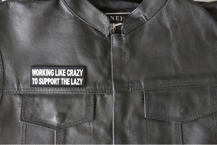 Working Like Crazy to Support The Lazy Patch - 4x1.5 inch - Embroidered Iron on Patch shown on leather vest