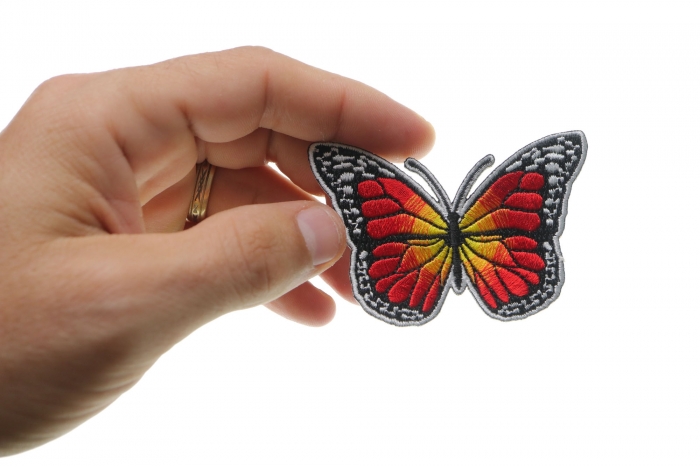 Orange Butterfly Iron On Patch shown on hand for size comparison
