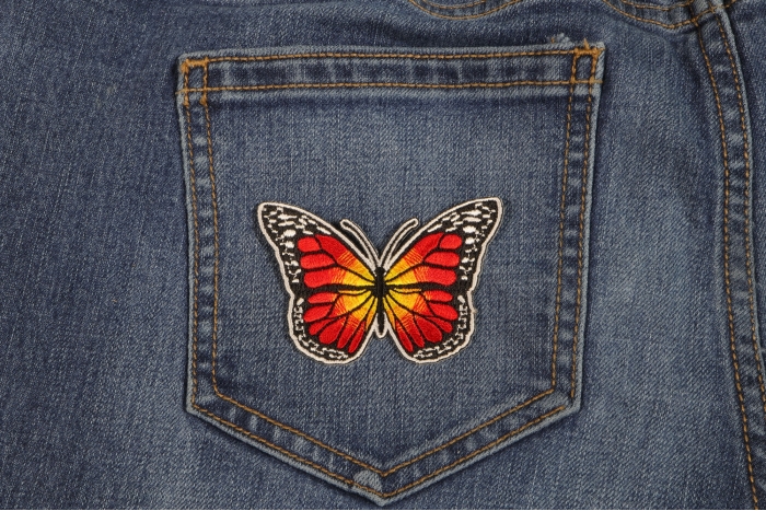 Orange Butterfly Iron On Patch shown on jeans