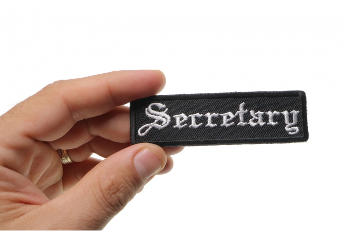 Secretary Patch In Old English shown on hand for size comparison