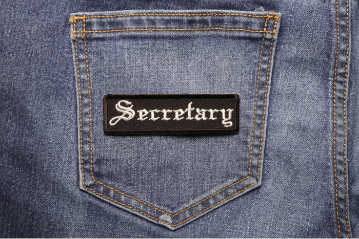 Secretary Patch In Old English shown on jeans