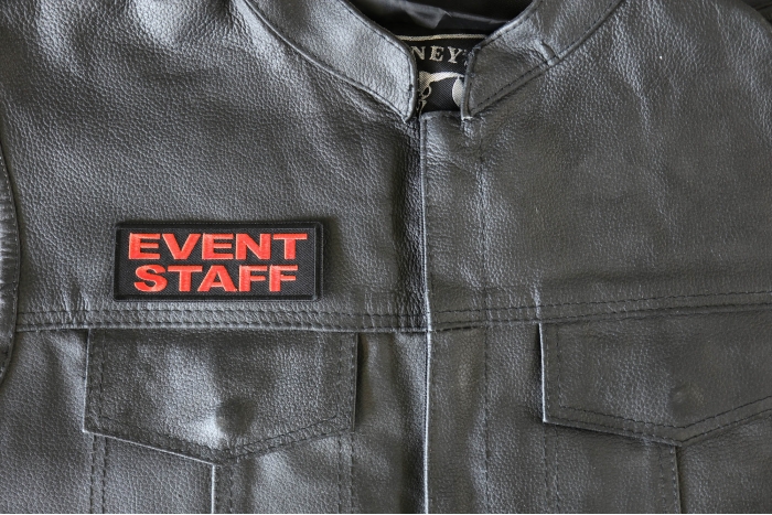 Event Staff Patch Orange - 4x1.5 inch - Embroidered Iron on Patch shown on leather vest