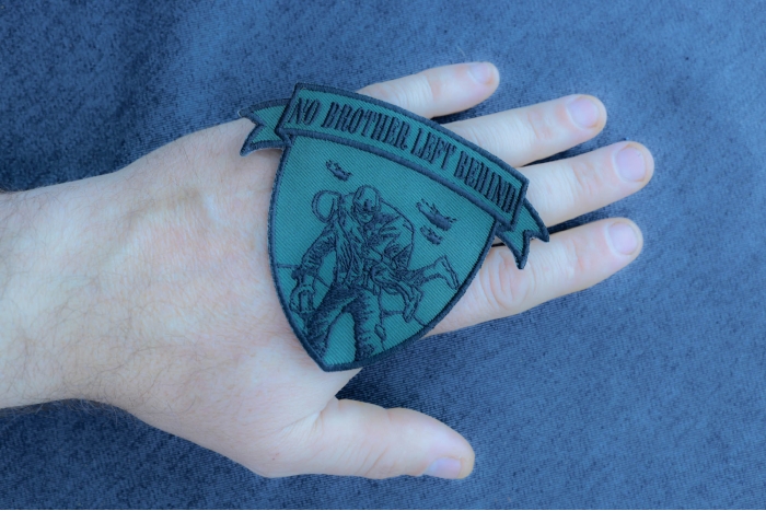 No Brother Left Behind Small Patch In Green Black shown on hand for size comparison