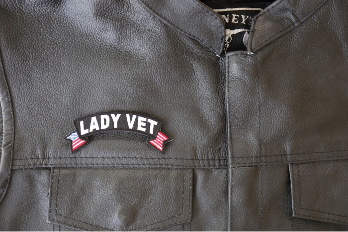 Lady Vet Small Flag Rocker Patch - 4x1.5 inch - Embroidered Iron on Patch shown on leather vest