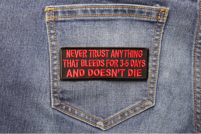 Never Trust Anything That Bleeds 5 Days And Doesn't Die Funny Iron on Patch shown on jeans