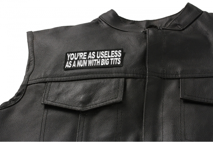 As Useless As A Nun With Big Tits Funny Patch - 4x1.5 inch. Embroidered Iron on Patch shown on leather vest