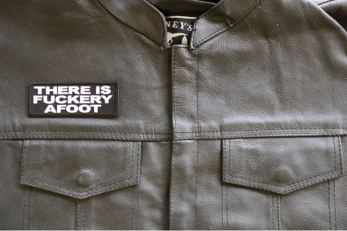 There is a Fuckery Afoot Iron on Patch shown on leather vest