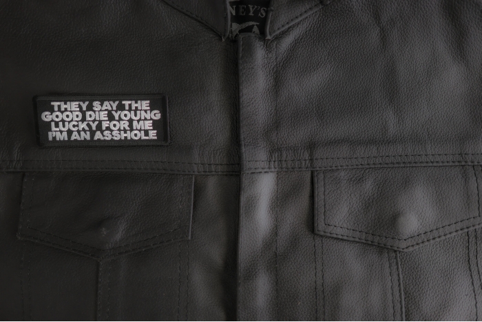 They Say The Good Die Young Lucky For Me I'm An Asshole Patch shown on leather vest