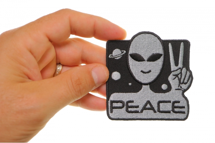 Peace Alien Fun Novelty Iron on Patch shown on hand for size comparison