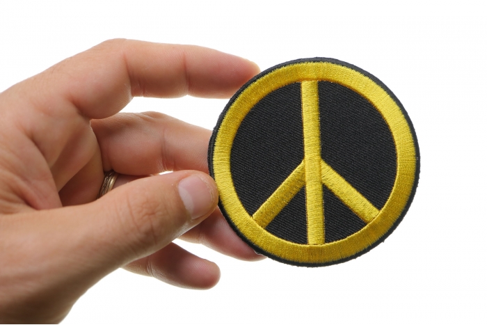 Peace Sign Iron on Patch Yellow On Black shown on hand for size comparison