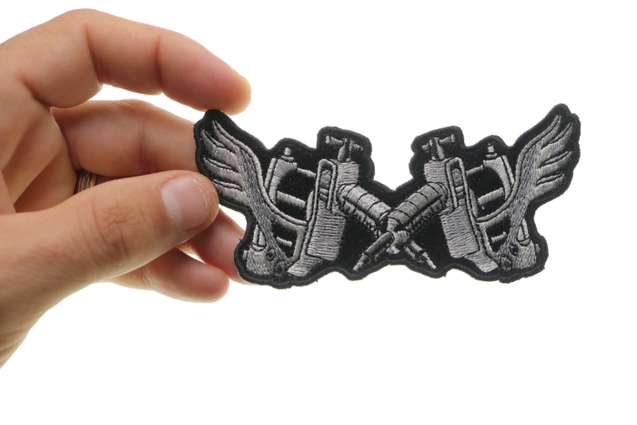 Tattoo Guns Wings Novelty Iron on Patch shown on hand for size comparison