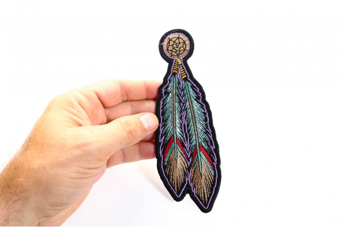 Feather Sew on Patch for Vests shown on hand for size comparison