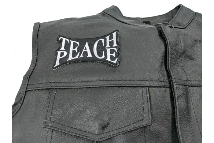 Teach Peace Patch - 4x2.5 inch. Embroidered Iron on Patch shown on leather vest