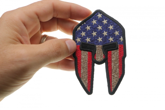 Spartan Helmet US Flag Patriotic Iron on Patch shown on hand for size comparison