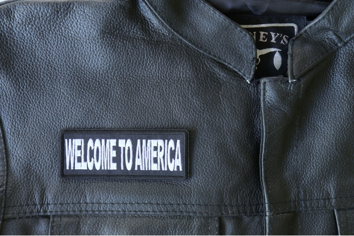 Welcome To America Patch - 4x1.5 inch - Embroidered Iron on Patch shown on leather vest