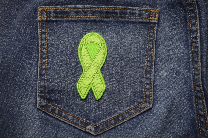 Green Ribbon Patch For Environmental Awareness shown on jeans
