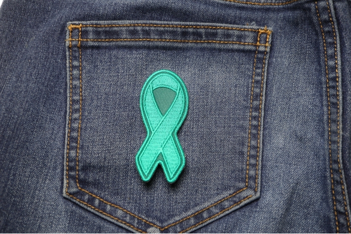 Teal PTSD Awareness Ribbon Patch shown on jeans