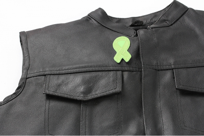 Green Ribbon Patch For Environmental Awareness - 3x1.25 inch. Embroidered Iron on Patch shown on leather vest